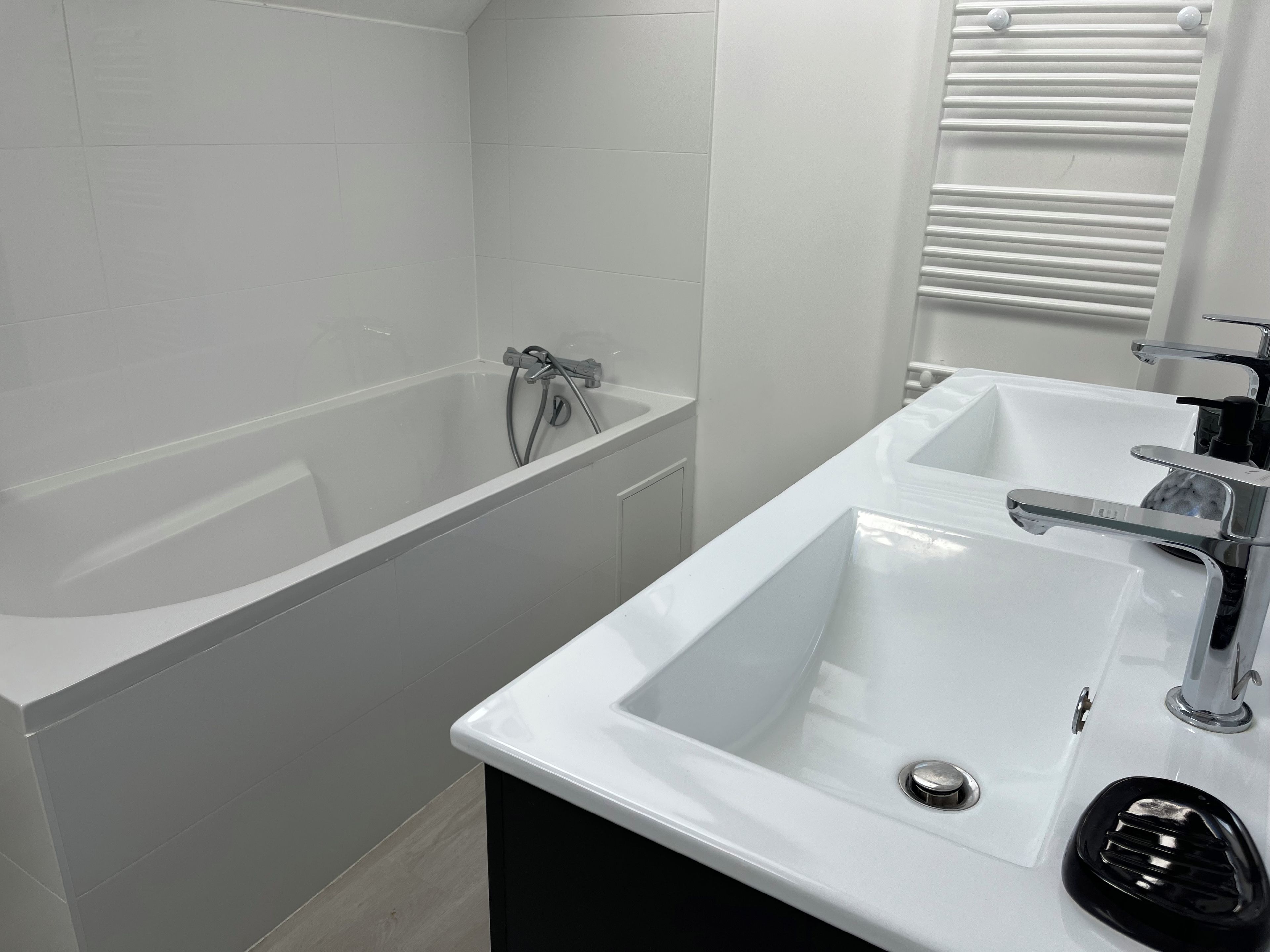 A bathroom with a bathtub, a sink, and a window with blinds.