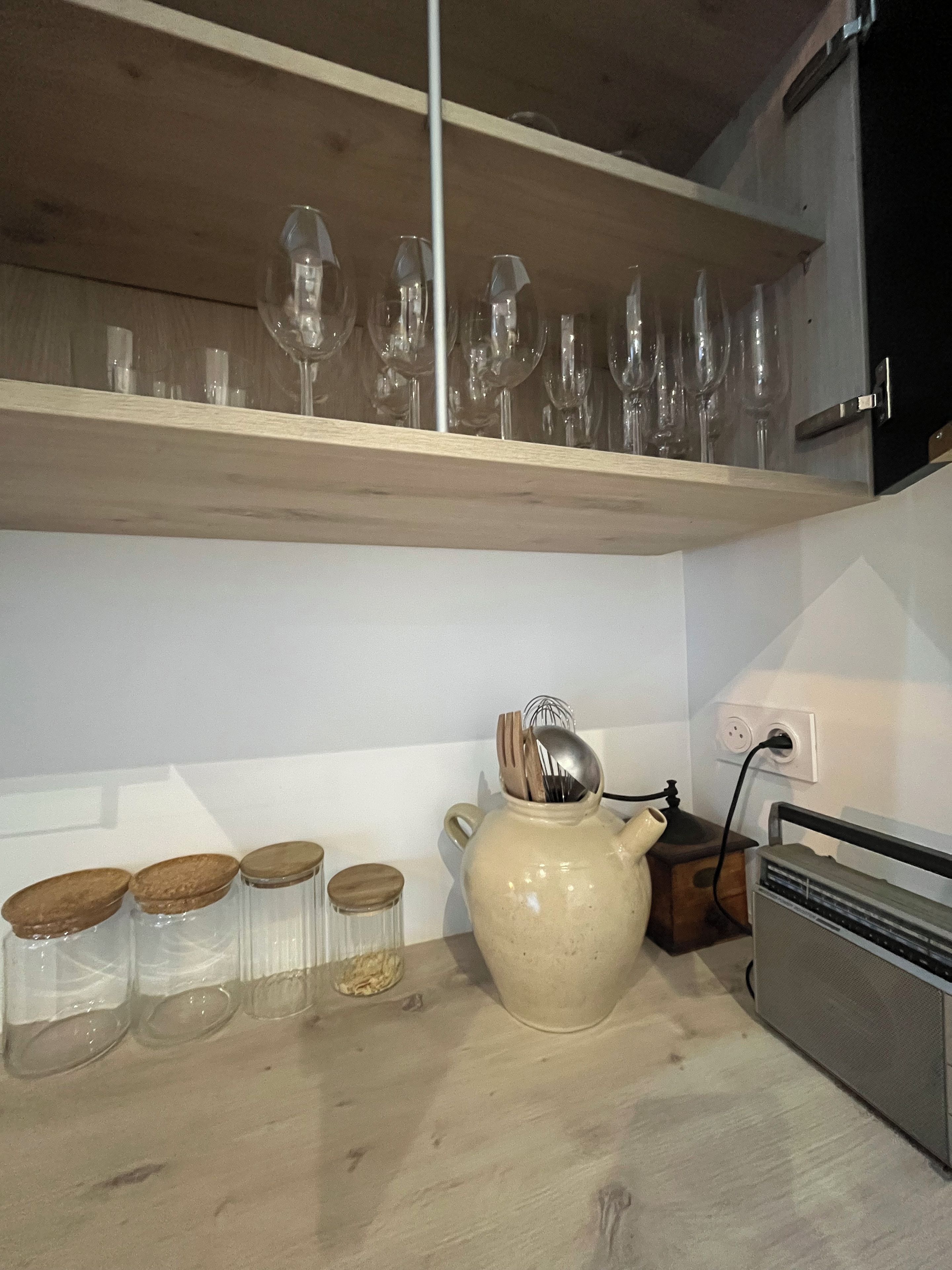 A kitchen counter with glass jars, a ceramic pitcher, and a speaker.