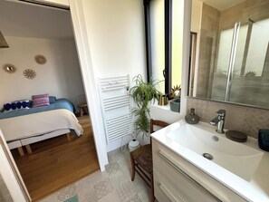 A modern bathroom with a large mirror, a white sink, and a shower area. - Bruisse Vacation Rental (Saint-Brieuc-des-Iffs)
