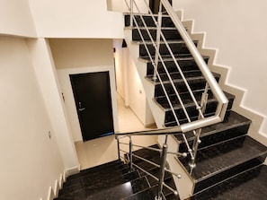 A modern staircase with black marble steps and stainless steel railings.
