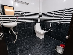 A modern bathroom with a white toilet, a sink, and a shower. - Hotel York Residency (Bhopal)