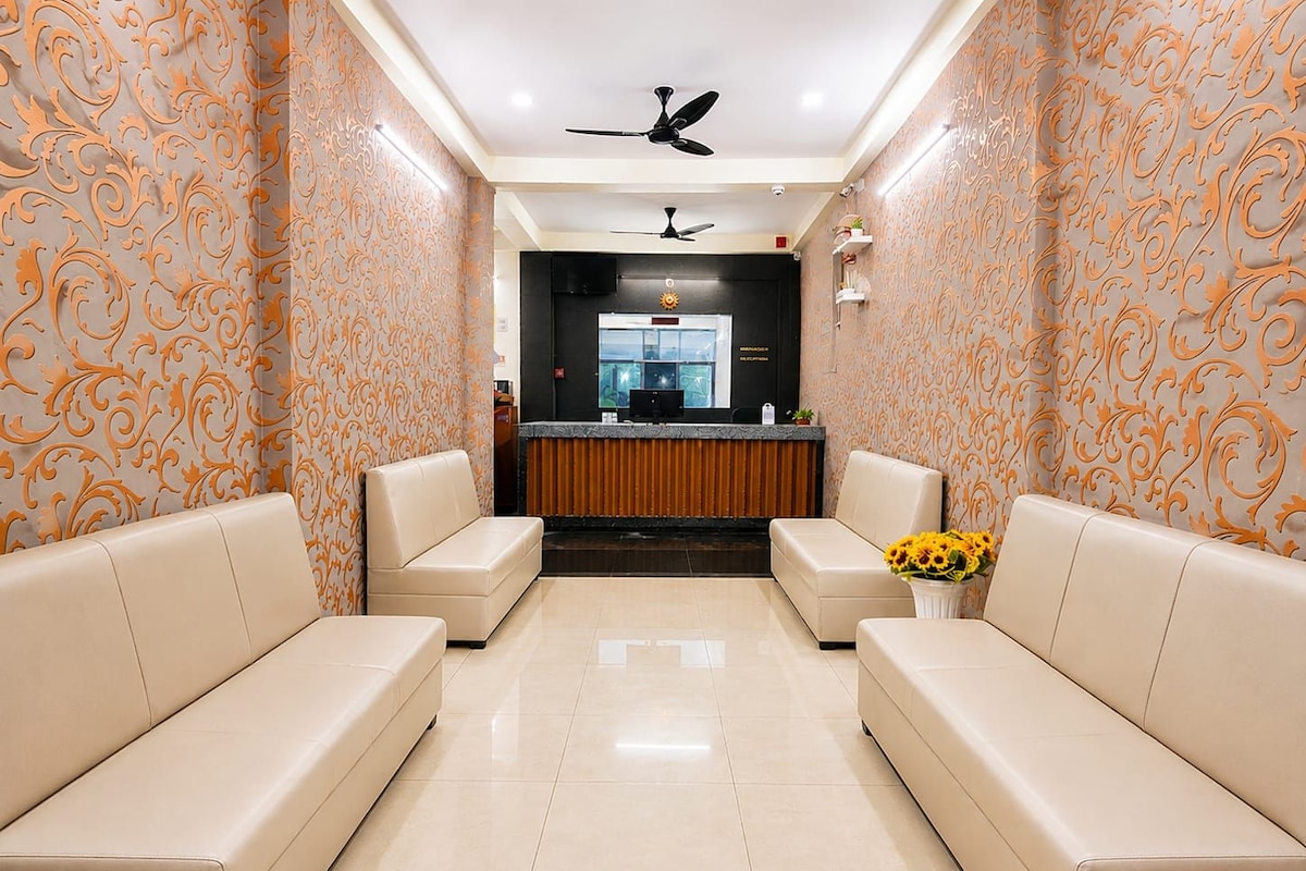 A reception area with a reception desk, two sofas, a ceiling fan, and a vase with sunflowers.