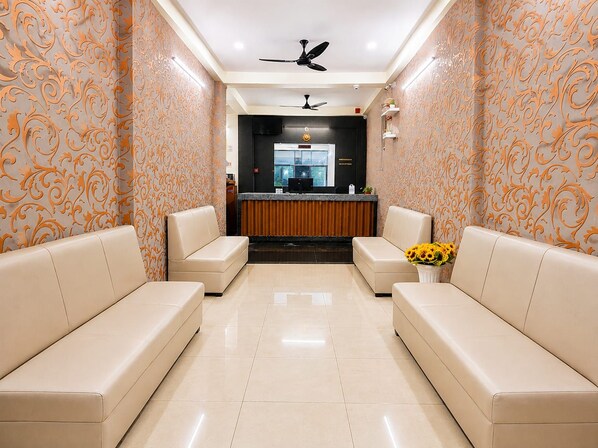 A reception area with a reception desk, two sofas, a ceiling fan, and a vase with sunflowers.