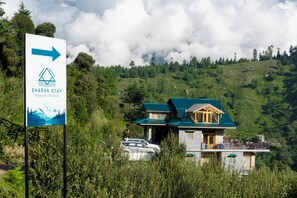 A mountain lodge with a sign indicating the direction to the Sharan Stay.