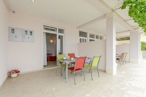 A covered outdoor dining area with a table and chairs, a door leading to an interior space, and a tiled floor. - Apartments Hope - Comfort Onebedroom Apartment With Terrace and Sea View (Dugi Rat)