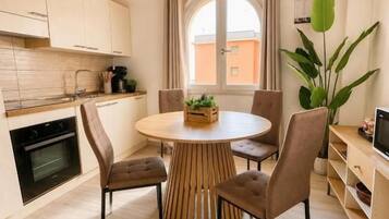 Una cocina moderna con armarios de madera, una mesa redonda con sillas y un amplio ventanal con cortinas.
