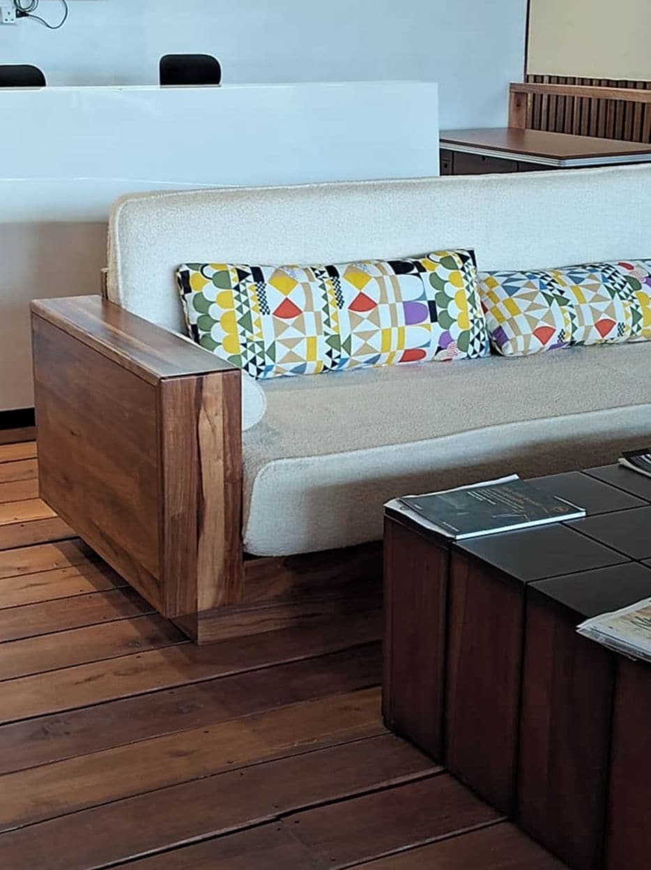 Ein modernes Wohnzimmer mit einer Couch, gemusterten Kissen, einem Holznachttisch und einem Couchtisch.