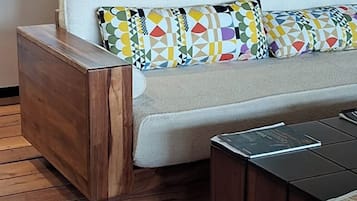 Ein modernes Wohnzimmer mit einer Couch, gemusterten Kissen, einem Holznachttisch und einem Couchtisch.