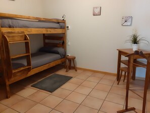 A bunk bed with a desk and chair, a small stool, and a potted plant.