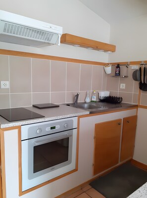 A kitchen with a built-in oven, a stovetop, a sink, and a countertop.