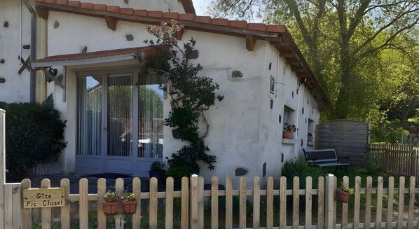 A white building with a tiled roof, a wooden fence, and potted plants.
