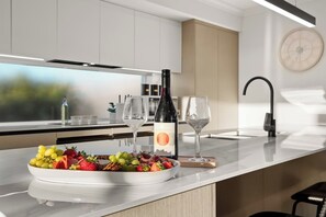 A modern kitchen with a marble countertop, a wine bottle, and a fruit platter.
