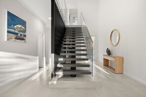 A modern interior with a staircase, a painting, and a console table.