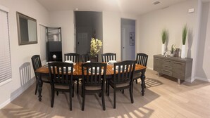 A dining area with a wooden table and black chairs, a dark door, and a grey cabinet with decorative items. - Vrbo Property (Haines City)
