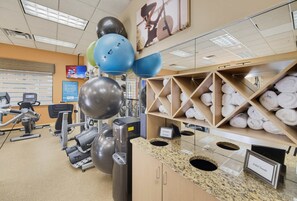 A gym with exercise equipment, a wall-mounted TV, and a towel rack. - Modern 2B Resort Condo Just 8 Minutes to Disney (Orlando)