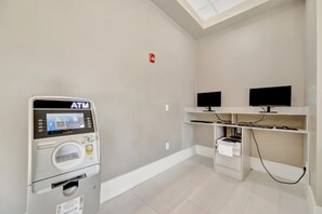 A room with a white ATM machine, a ceiling light, and a TV on a shelf. - Modern 2B Resort Condo Just 8 Minutes to Disney (Orlando)