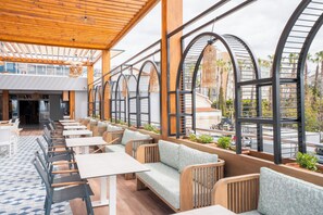 A restaurant with outdoor seating, wooden tables, and chairs, and a view of the street. - Mira Meridia Beach Resort Hotel (Alanya)