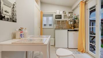 Cocina compacta con microondas, cafetera y refrigerador pequeño.