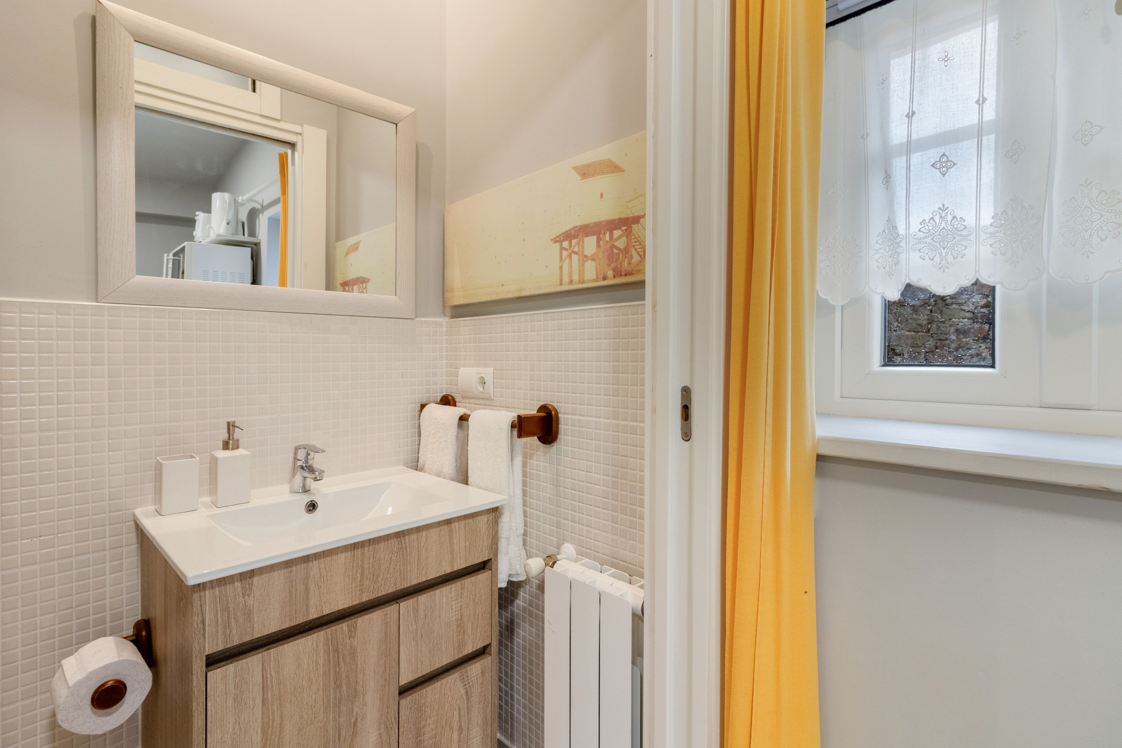 Een badkamer met een wit wastafel, spiegel en betegelde wanden.