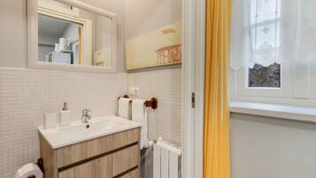 Een badkamer met een wit wastafel, spiegel en betegelde wanden.