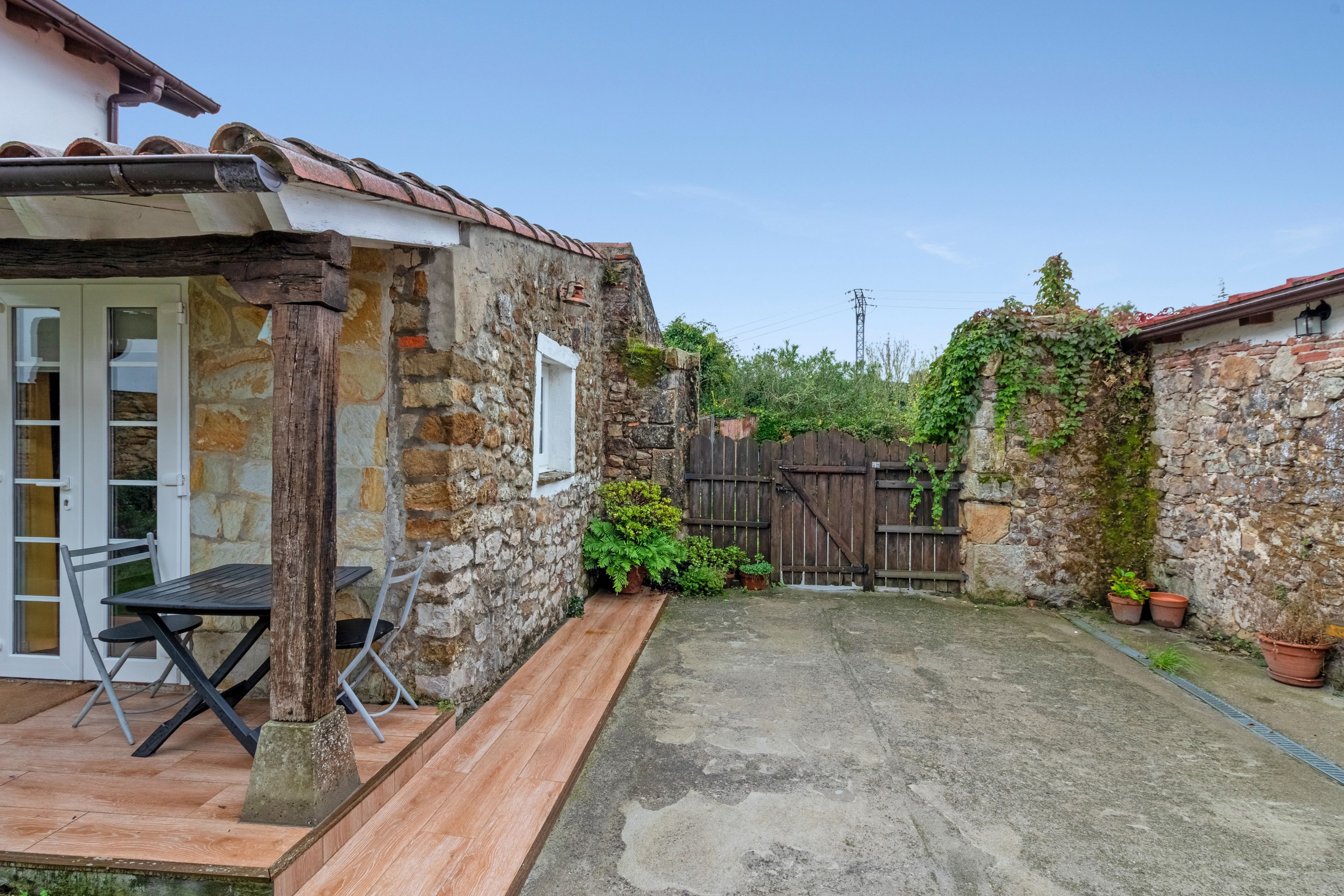 A stone building with a wooden deck and a table with chairs.