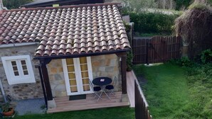 A house with a tiled roof, a patio with outdoor furniture, and a fenced yard. - Holiday Home 'Estudio Minimalista En Galizano' with Private Terrace, Private Garden and Wi-Fi (Cantabria)