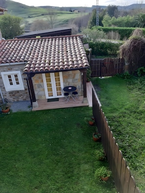 Une maison avec un toit en tuiles, une terrasse avec des meubles d’extérieur et une cour clôturée.