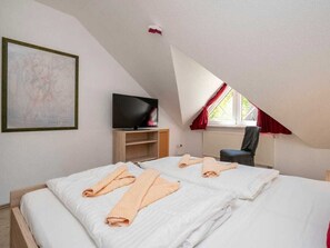 Ein Schlafzimmer mit einem Bett, einem Fernseher, einem Sessel und einem Fenster.