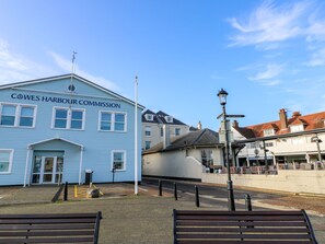 A blue building labeled 'Cowes Harbour Commission' with a street lamp and benches in the foreground. - Serenity Thorness Bay (Cowes)