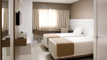 Quarto de hotel com duas camas, uma escrivaninha, uma cadeira, uma televisão e uma janela com cortinas.