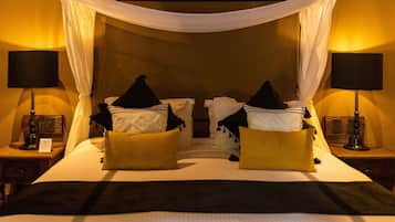Una cama con dosel, dos mesitas de noche con lámparas y almohadillas.