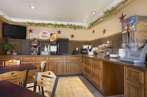 A breakfast area with a coffee machine, a refrigerator, and a counter with a cereal dispenser.