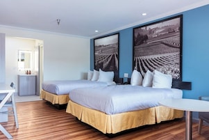 A hotel room with two beds, a small table, and a view of a vineyard.