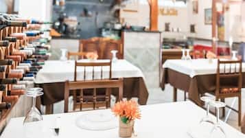 Interior de un restaurante con mesas dispuestas para comer, una bodega de vinos y un centro de mesa con flores.