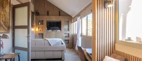 Ein modernes Interieur mit einer Couch, Sesseln, einem Fernseher und einem Essbereich.