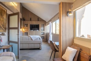 A modern interior with a sofa, chairs, a television, and a dining area.