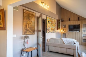 A modern living room with a sofa, a table with a lamp, and artwork on the walls.