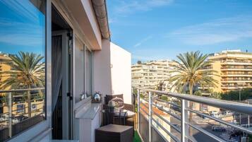 Un balcón con vista a un paisaje urbano, incluyendo palmeras y edificios de varios pisos.