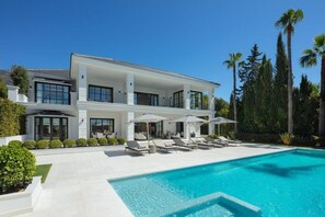 A modern two-story house with a swimming pool, outdoor seating, and a landscaped garden. - Villa In Sierra Blanca - 2398 (Marbella)