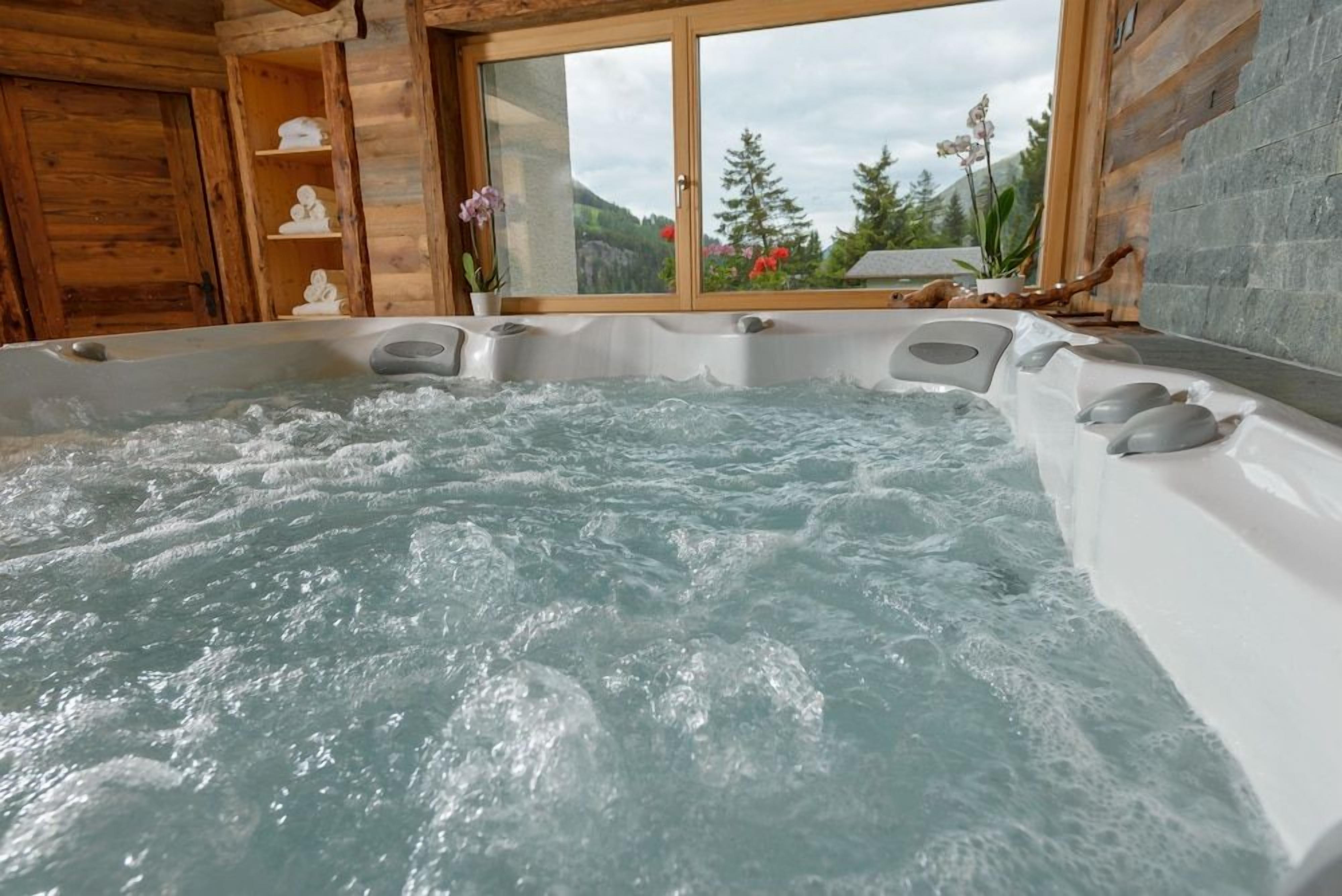 Un jacuzzi con vistas a un paisaje montañoso a través de una ventana.