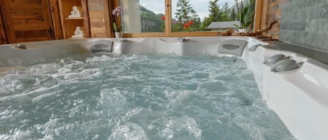 Un jacuzzi con vistas a un paisaje montañoso a través de una ventana.