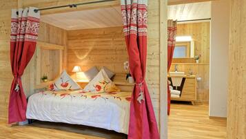 Ein Schlafzimmer einer Holzhütte mit Bett, Vorhängen und einem Badezimmer.