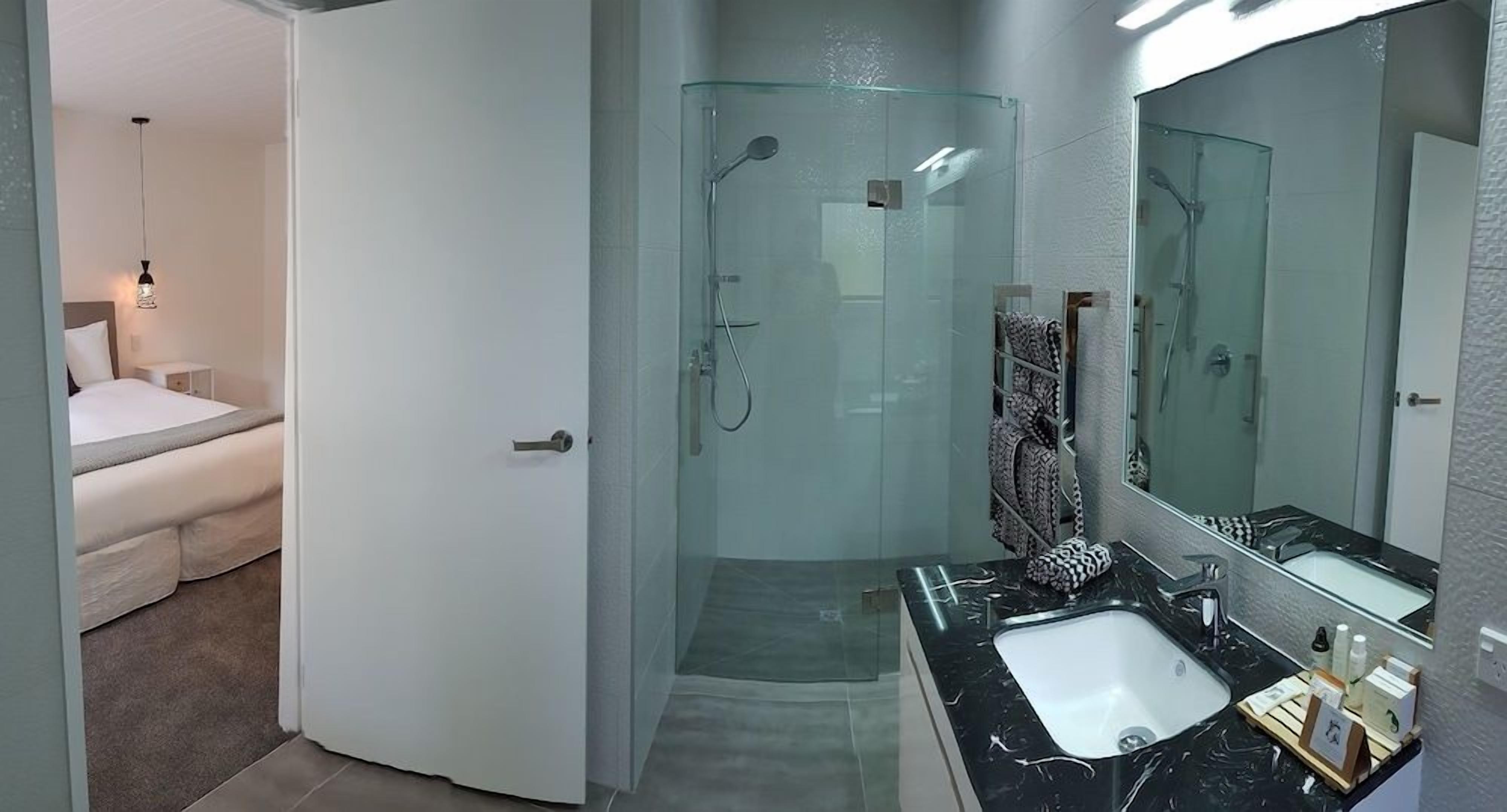 A modern bathroom with a glass-enclosed shower, a large mirror, and a vanity with a sink.