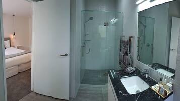 A modern bathroom with a glass-enclosed shower, a large mirror, and a vanity with a sink.