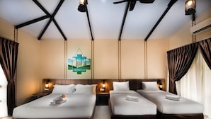 A hotel room with a large bed, two smaller beds, a decorative wall piece, and a ceiling fan. - Paya Beach Resort (Tioman Island)