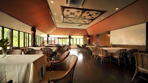 A spacious dining area with high ceilings and large windows, featuring tables and chairs arranged for groups. - Paya Beach Resort (Tioman Island)