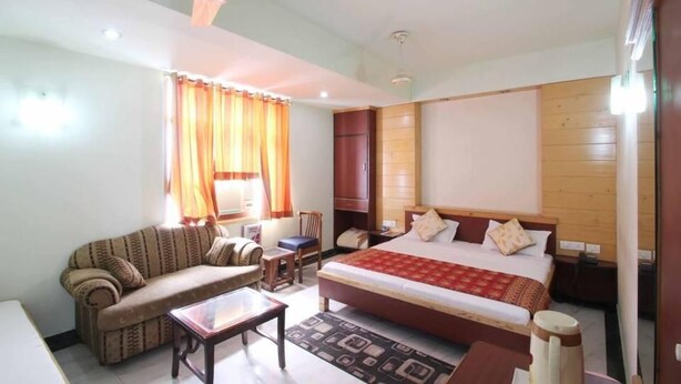 A hotel room with a bed, a sofa, a desk, and a chair. - Hotel S R Palace (Agra)