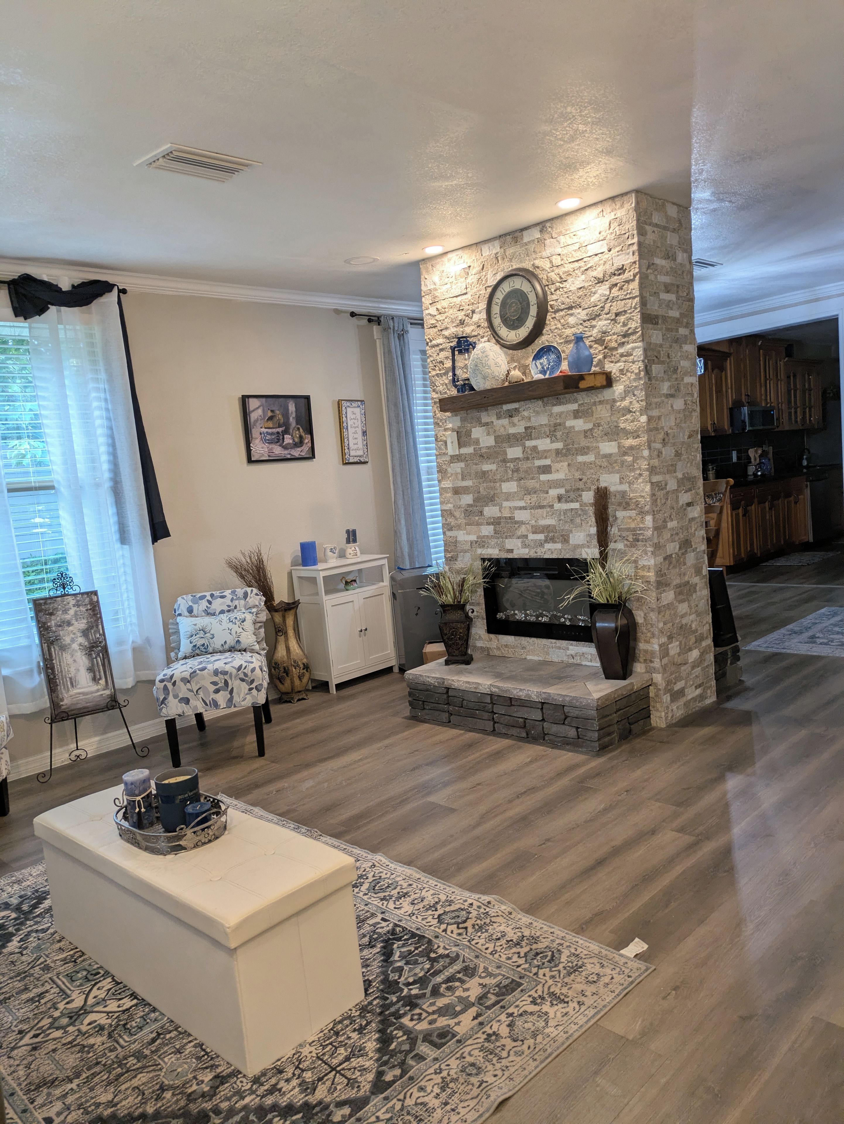 A living room with a fireplace, a white sofa, a coffee table, and a patterned rug.