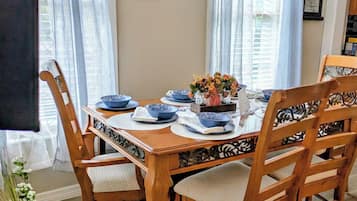 Comedor con una mesa de madera dispuesta para seis personas, rodeada de sillas con asientos acolchados.