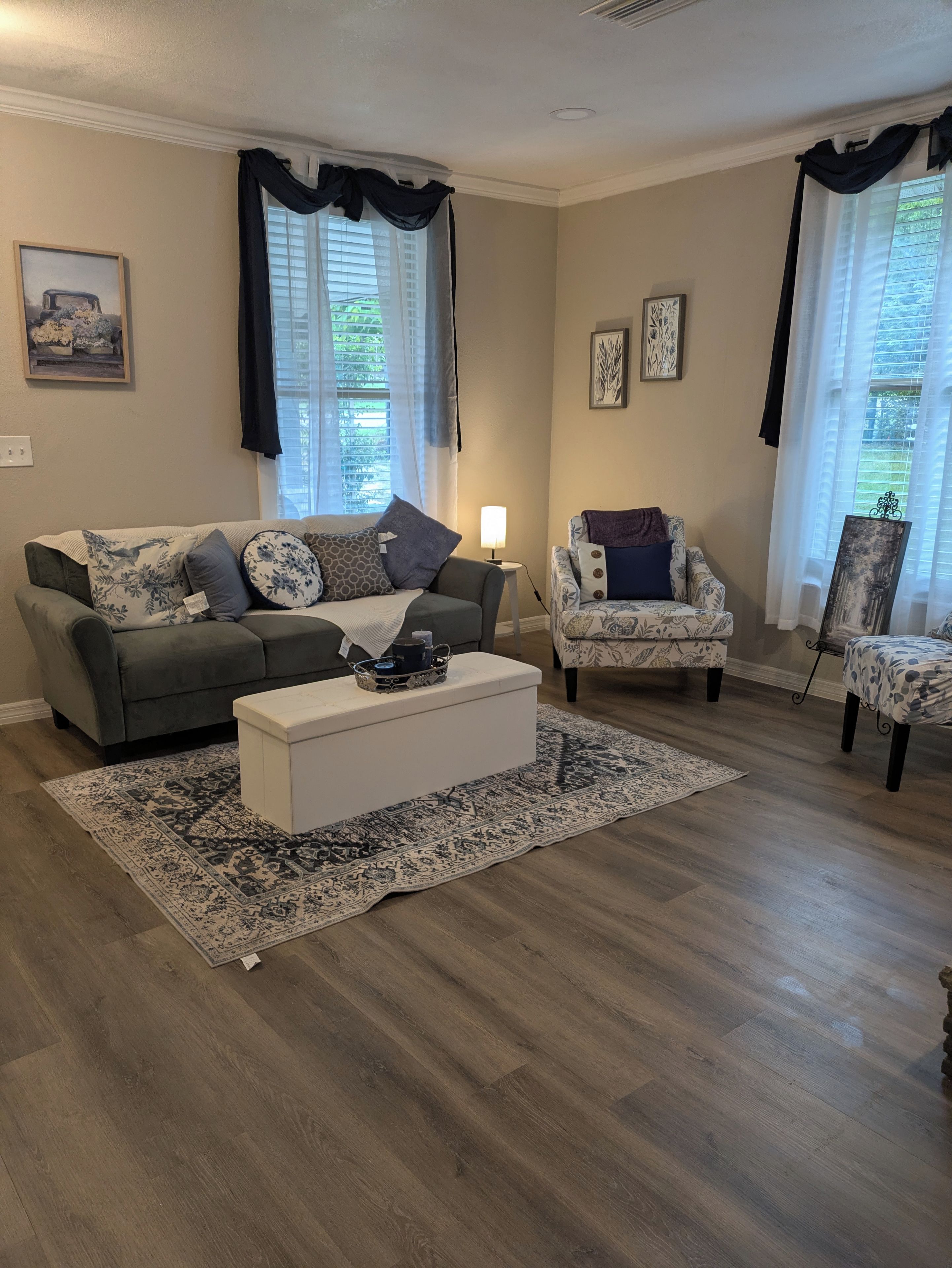 A living room with a grey sofa, a white coffee table, patterned rugs, and two armchairs.